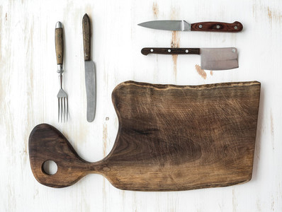 Kitchen ware set  Old rustic chopping board made of walnut wood  knives  fork on a white background