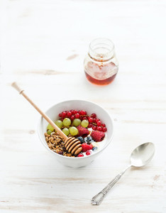 Healthy breakfast Bowl of oat granola with yogurt fresh berries fruit and honey Top view