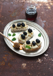 Italian bruschetta sandwich with brie cheese  honey and blackberry on vintage silver tray over grunge rusty metal background  top view