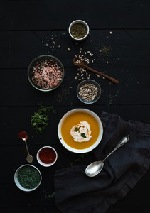 Pumpkin soup with cream  seedsand various spicesl in rustic metal bowl over grunge black background  Top view
