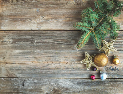 Christmas or New Year rustic wooden background with toy decorations and fur tree branch  top view