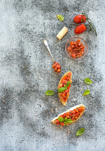 Tomato and basil bruschetta sandwich over grunge gray background top view