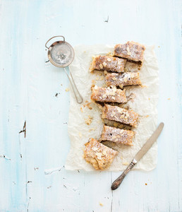 Homemade apple and almond strudel on baking paper over light blue wooden backdrop