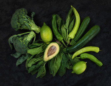Raw green vegetables set  Broccoli  avocado  pepper  spinach  zuccini and lime on  dark stone background
