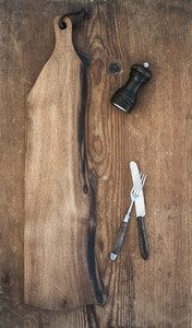 Kitchen ware set  Old rustic serving board  knive and fork  pepperbox on a old wooden background