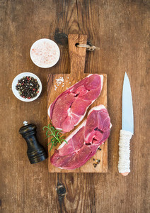 Raw fresh meat lamb entrecote and seasonings on cutting board over rustic wooden background