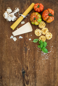 Ingredients for cooking pasta  Spaghetti  tagliatelle  garlic  Parmesan cheese  tomatoes and fresh basil on rustic wooden background  top view  copy space