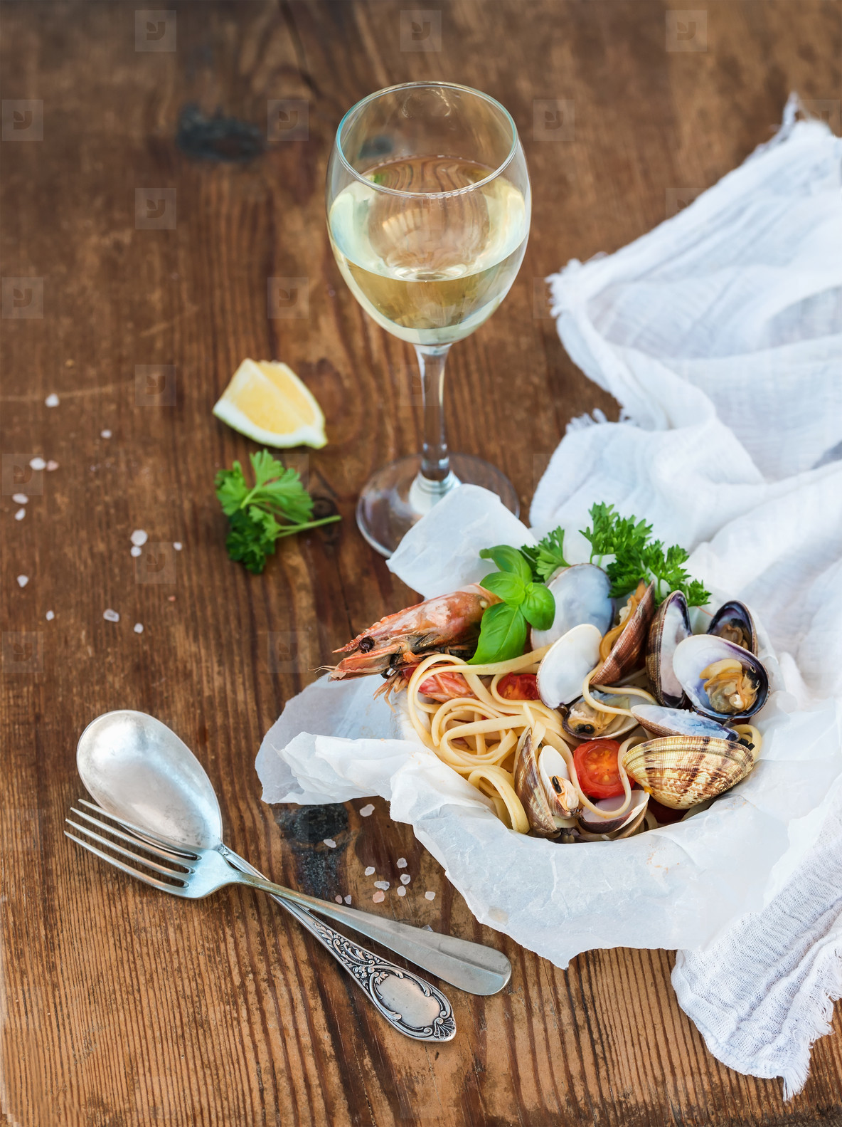 Seafood pasta  Spaghetti with clams and shrimps in bowl  glass of white wine over rustic wood background