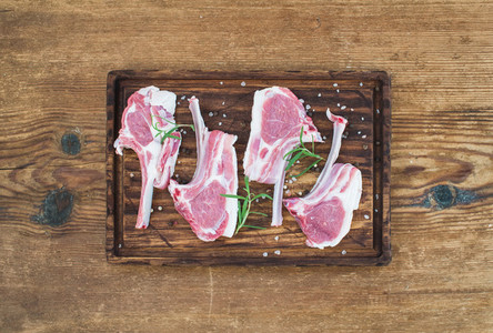 Rack of Lamb with rosemary and spices on rustic chopping board over old wooden background