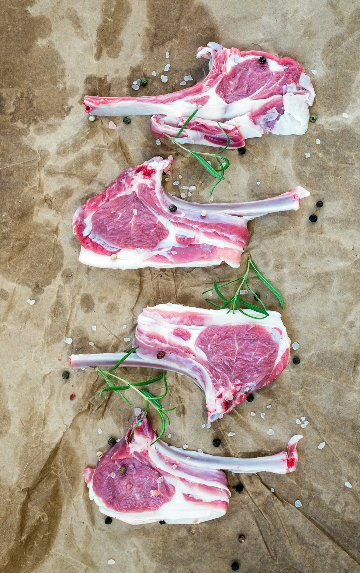 Rack of Lamb with rosemary and spices over oily craft paper background