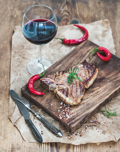 Cooked meat t bone steak on serving board with roasted tomatoes
