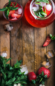 Homemade strawberry mint lemonade served with fresh berries and ice over wooden background  top view  copy space
