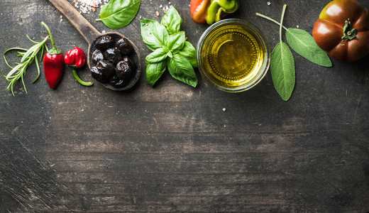 Food background with vegetables  herbs and condiment  Greek black olives  fresh basil  sage  rosemary  tomato  peppers  oil on dark rustic wooden background