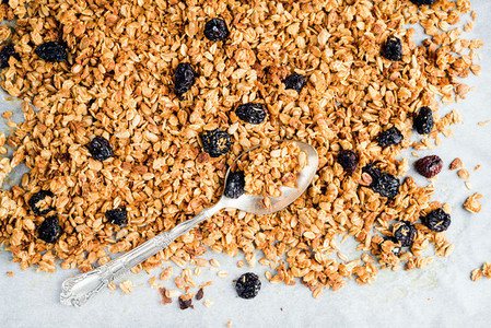 Homemade oat  cherry and coconut granola over baking paper with spoon