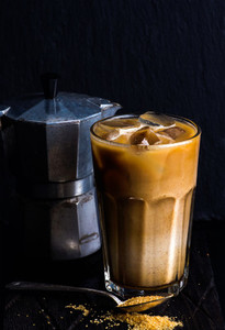 Iced coffee with milk in a tall glass  moka pot  black background