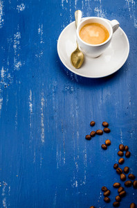 Cup of espresso coffee and beans on wooden blue painted table