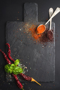 Herbs and spices on black slate stone board over dark background
