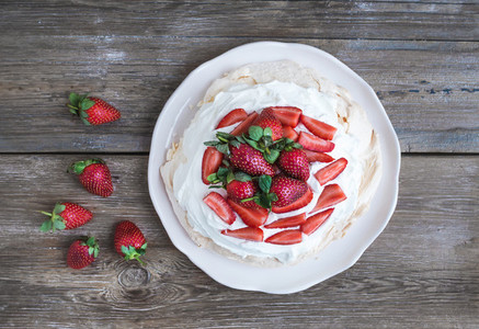 Rustic Pavlova cake with fresh strawberries and whipped cream ov
