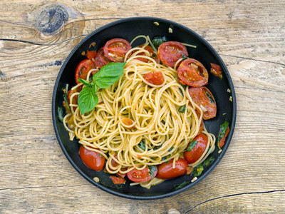 A pan of spaguetti with tomatoes and basil