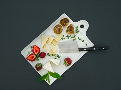 Cheese and fruit set on a dark surface