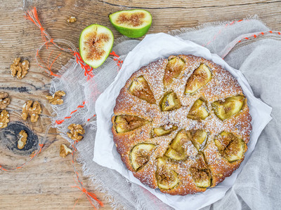 Fig cake with fresh figs and walnuts over a rough wood surface