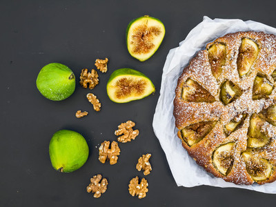 Fig pie with fresh figs and walnuts on black