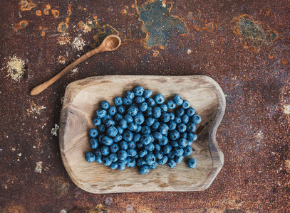 Blueberries in a rustic wooden serving dish over grunge metal rusty background