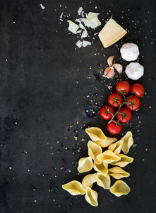 Food frame  Pasta ingredients  Cherry tomatoes  pasta  garlic  basil  parmesan and spices on dark grunge backdrop  copy space