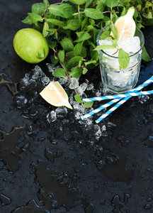Mojito cooking set  Bunch of fresh mint  lime  chipped ice and coctail glass over black slate stone backdrop