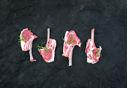 Raw lamb chops Rack of Lamb with rosemary and spices over black slate stone background