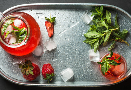 Homemade strawberry lemonade mint and ice served with fresh berries in metal tray top view