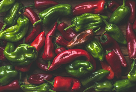 Background of colorful red and green bell peppers over wooden backdrop