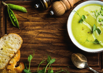 Green pea cream soup on wooden background copy space