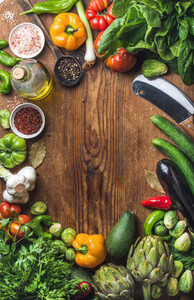 Fresh raw vegetable ingredients for healthy cooking or salad making on wooden background copy space in center top view Diet  vegetarian food concept