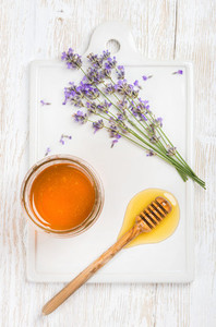Lavender honey in glass jar with flowers on white background