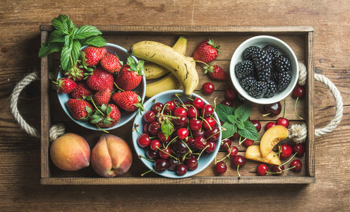 Summer fresh fruit and berry variety in rustic wooden tray