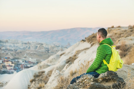Young man sitting at edge of cliff  Cappadocia  Central Turkey