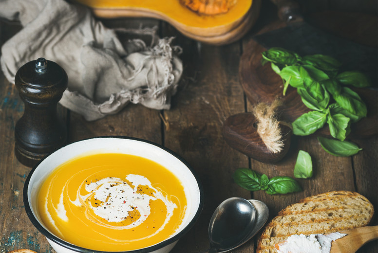 Pumpkin cream soup with fresh green basil, spices, grilled bread