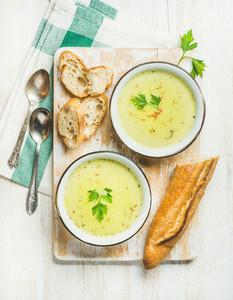 Green vegetable soup with parsley and baguette on wooden board