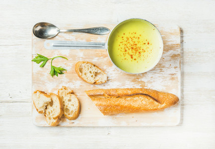 Green vegetable soup in scoop with parsley and baguette