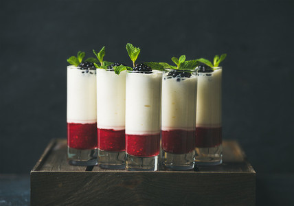 Dessert in glass with blackberries and mint over dark background