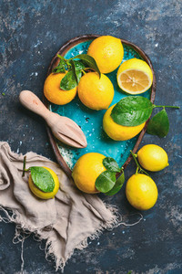 Freshly picked orange lemons with leaves in blue ceramic plate