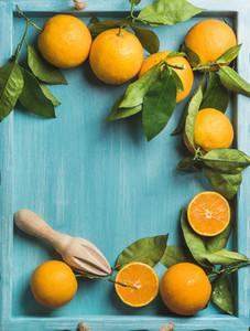 Fresh oranges with leaves on blue painted wooden background  copy space