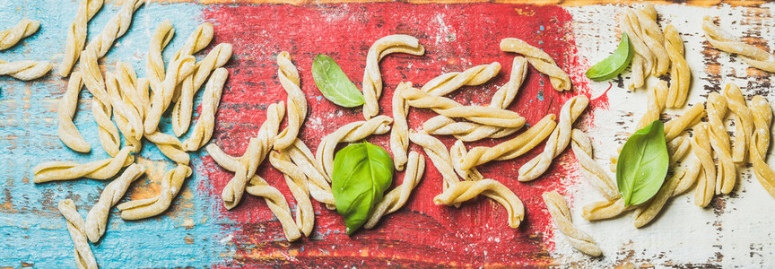 Homemade uncooked pasta casarecce with flour and green basil leaves