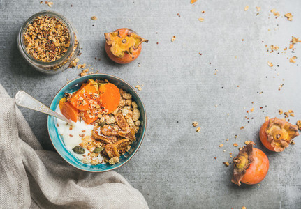 Healthy vegetarian breakfast in blue bowl and fresh persimmon