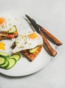 Breakfast toast with vegetables and fried egg on white plate