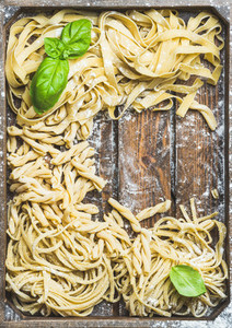 Various homemade uncooked Italian pasta in wooden tray