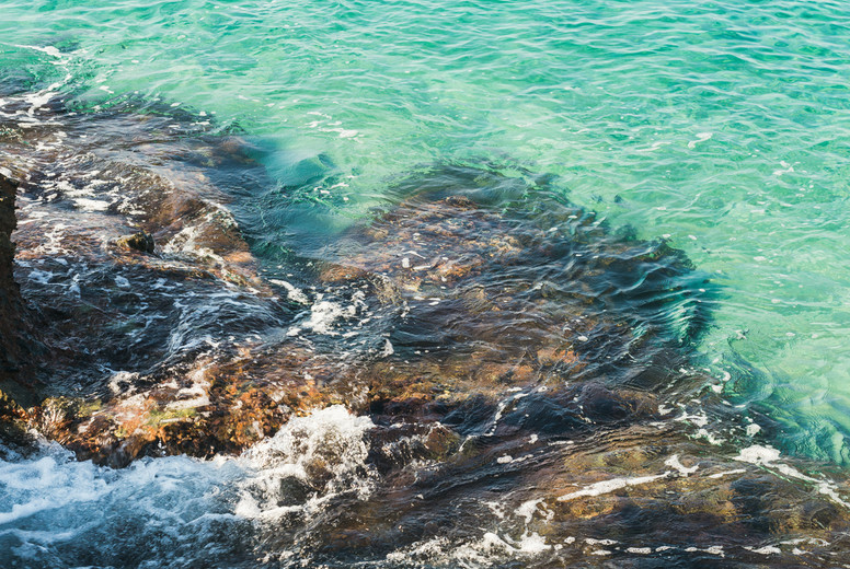 Natural rocks and clear blue waters at Kleopatra beach, Alanya