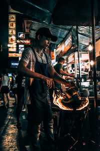 Man on street cooks with pan