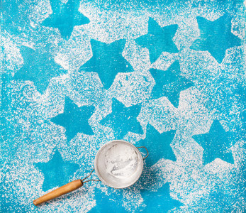 Sieve with sugar powder over bright blue background